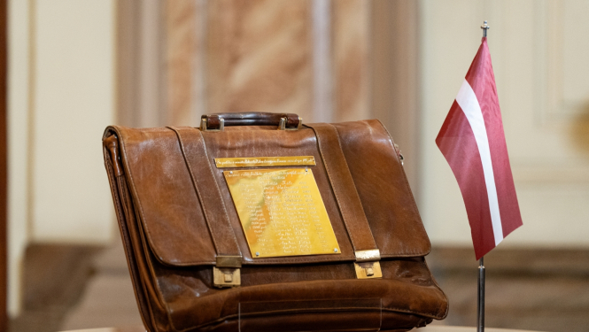 Budžeta portfelis uz galda līdzās Latvijas karogam