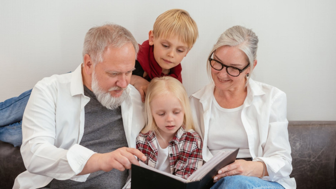 Bērni ar vecvecākiem skatās grāmatu
