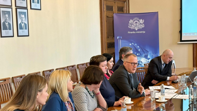 Vīrieši un sievietes sēž rindā pie gara galda