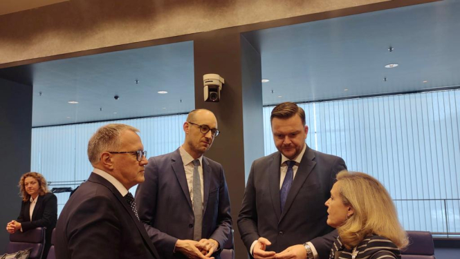 Četri cilvēki stāv viens pret otru un sarunājas