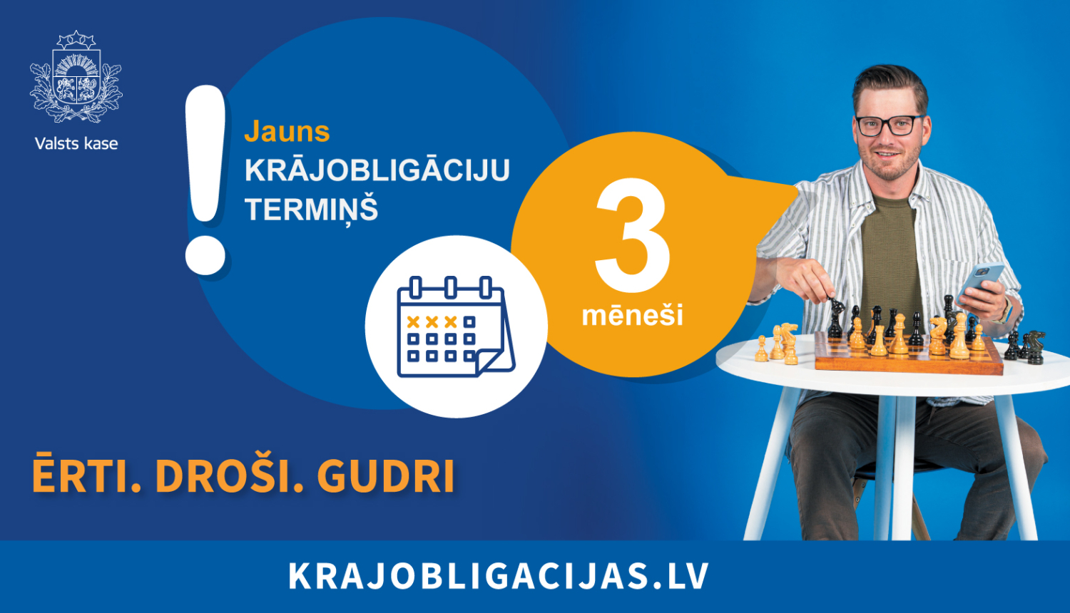 Attēlā ir redzams vīrietis, kurš sēž pie neliela galdiņa, uz kura ir šaha laukums ar figūrām, attēlu papildina teksts