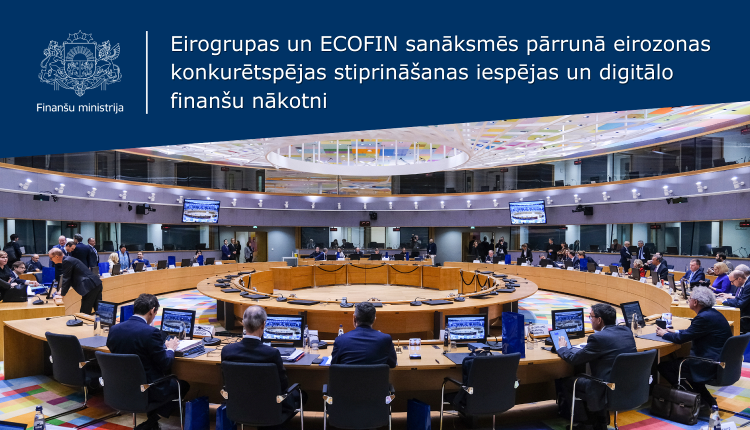 Attēlā redzams skats no zāles, kurā daudz cilvēku sēž pie vairākos apļos izkārtotiem galdiem