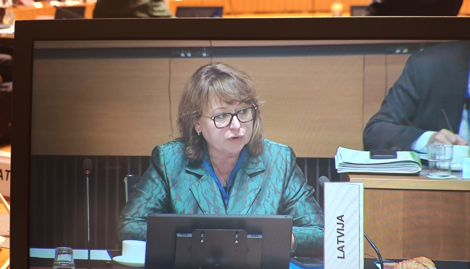 Attēlā redzama sieviete, kura uzstājas konferencē ar uzrunu