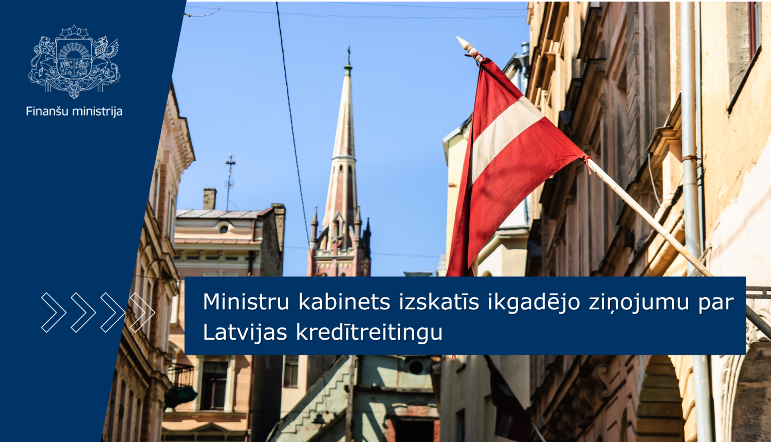 Attēlā redzama kāda Rīgas iela, foto centrā - mastā plīvojošs Latvijas karogs. Uz attēla ir teksts